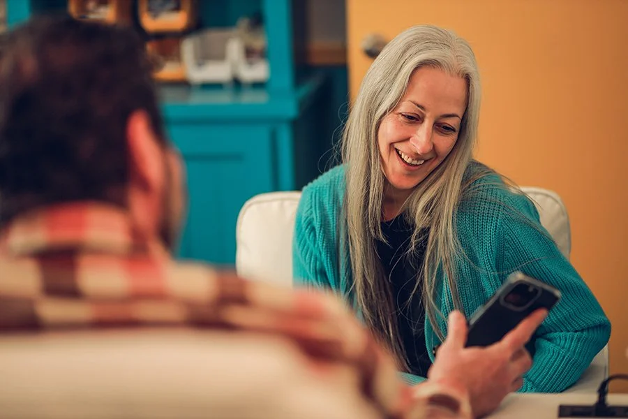 Smiling woman with gray hair looking at her phone