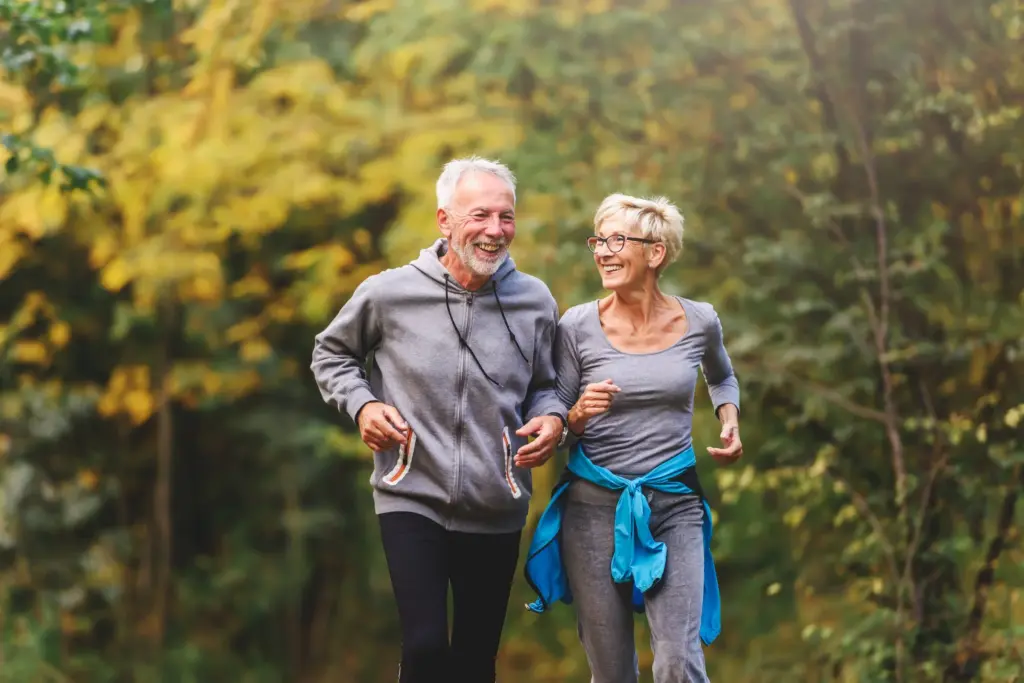 Older couple jogging together on a wooded trail