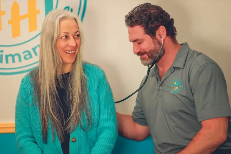 Matthew Simone, FNP-BC, listening to a patient's heart with a stethoscope