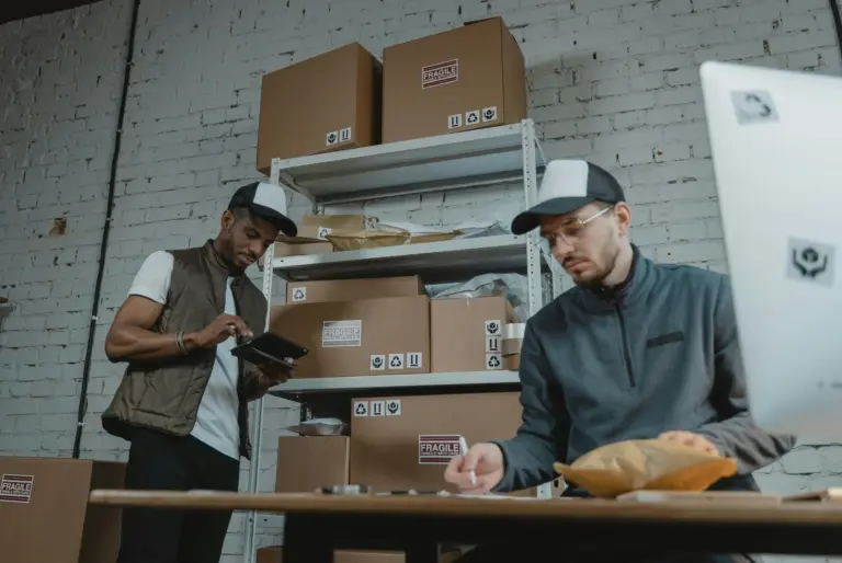 Workers in a small warehouse surrounded by boxes