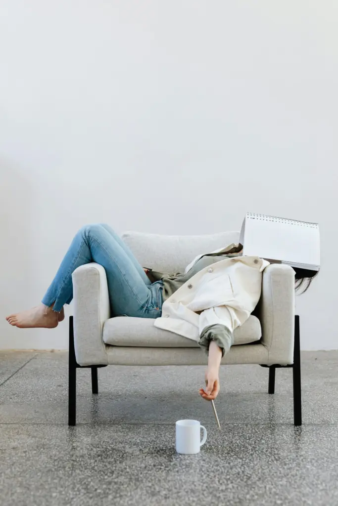 Person lying exhausted on a couch in an empty room