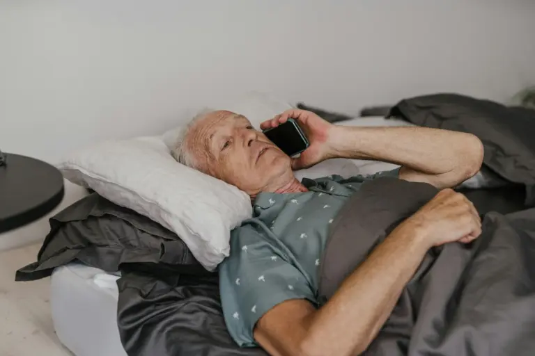 Older man resting in bed while talking on the phone